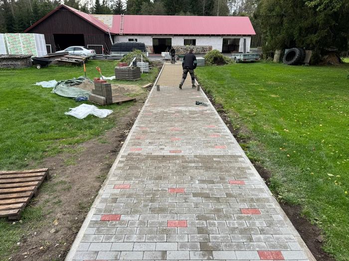 Tänavakivist tee ehitus õuealal, kaks töölist paigaldamas